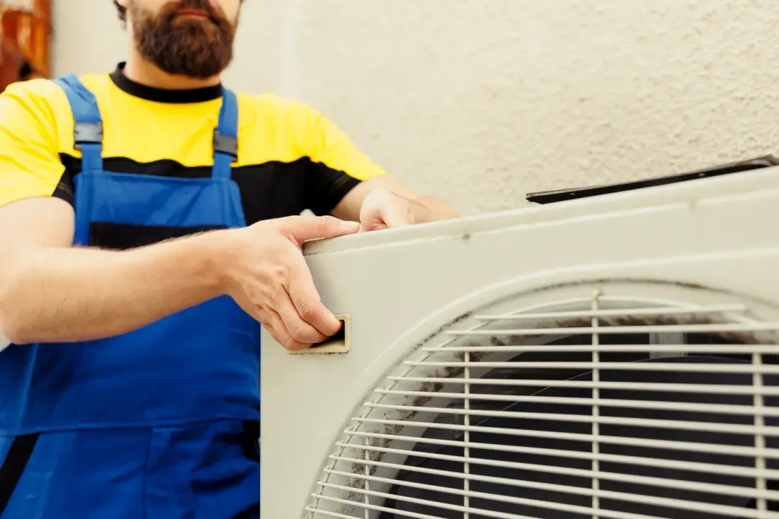 An HVAC technician installing a residential central air conditioning unit