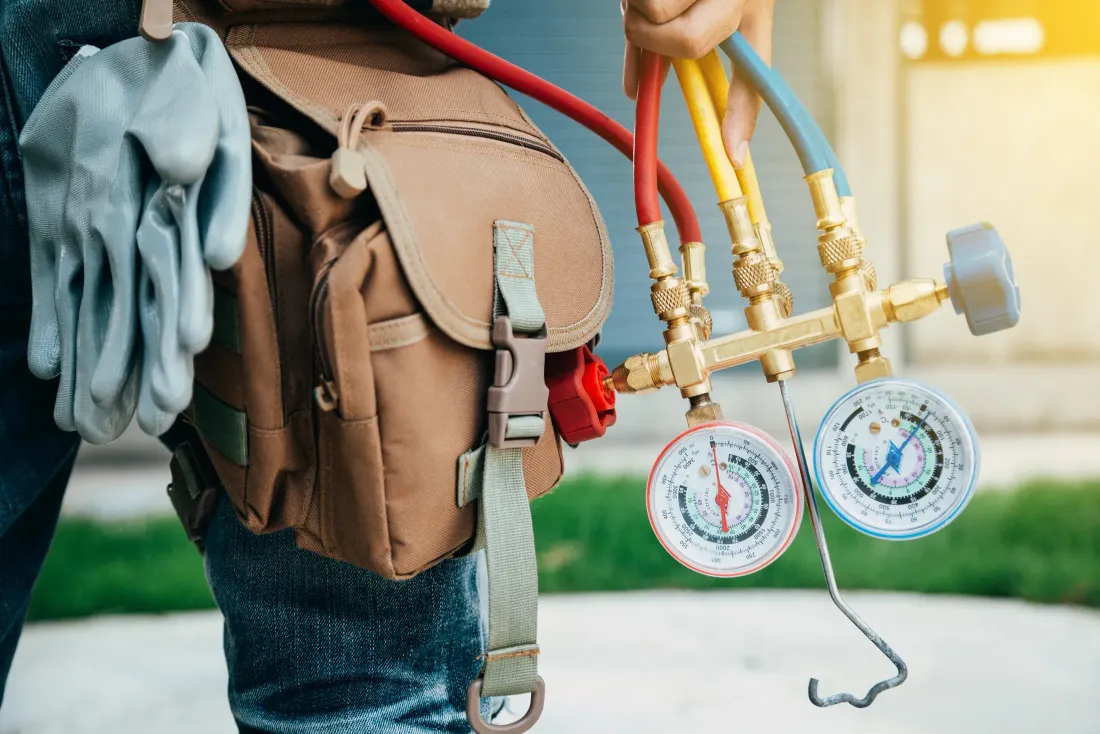 An HVAC technician working on a residential air conditioning system